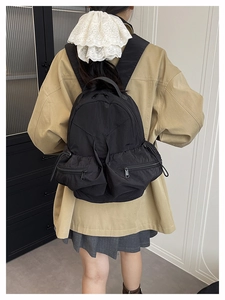 Rear view of black nylon utility backpack with dual zipper pockets on female model