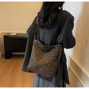 Detail view of large leopard print bucket bag with brown leather trim and shoulder strap