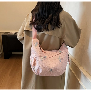 Close-up of pink butterfly embroidery and embossed texture on large canvas crossbody bag