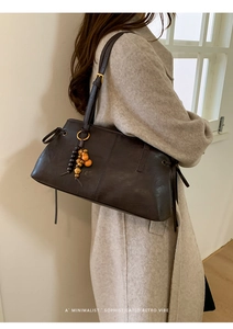Detailed view of dark brown leather tote with wooden beads and gourd pendant accessory