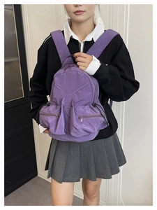 Detail of purple nylon backpack with water-resistant pleated texture and dual front pockets