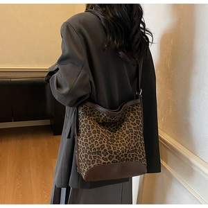 Close-up of leopard print bucket bag with brown leather trim and shoulder strap detail