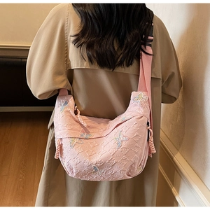 Pink crescent crossbody bag with 3D butterfly patches and embossed texture on model