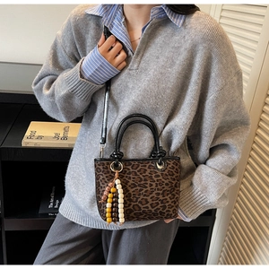 Détail du sac seau à imprimé léopard avec poignées noires et perles de bois colorées