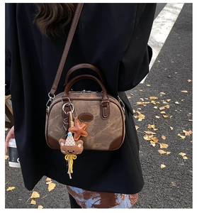 Outdoor shot of a vintage brown leather pillow bag with star and bear charms on street background