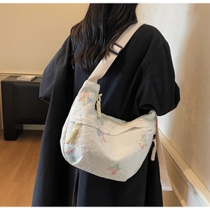 Detail of white moon bag featuring colorful butterfly embroidery and wide shoulder strap