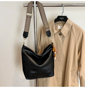 Close-up of black matte hobo bag with geometric woven strap and wooden bead detail