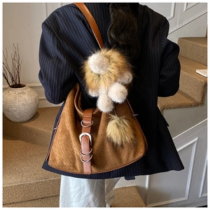 Detailed texture of brown woven leather shoulder bag with a soft faux fur pompom charm