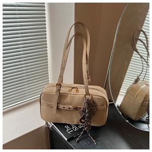 Detailed close-up of a beige leather shoulder bag featuring dual zippers and gold hardware