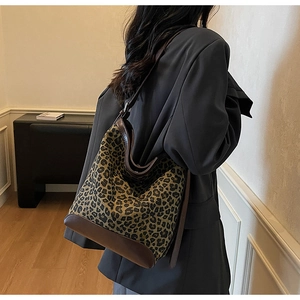 Detail view of large leopard print bucket bag with premium brown leather stitching and strap