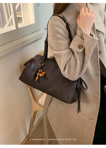 Detail of dark brown tote bag with leather drawstrings and beaded tassel charm accessory