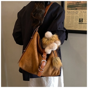 Detail of vintage woven brown bucket bag with plush pom-poms and metal hardware charms