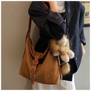 Detailed texture of brown woven tote bag with metal buckle and teddy bear charm