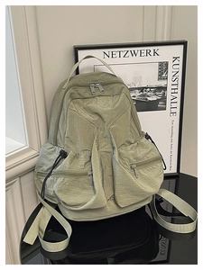 Detailed view of light green nylon backpack with textured fabric and dual front zip pockets
