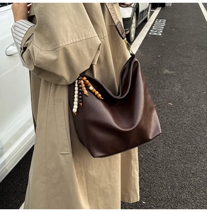 Detail of soft brown leather bucket bag with bohemian tassel and patterned strap