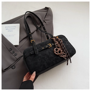 Black suede underarm bag with vintage metal buckle and decorative charms on grey blazer
