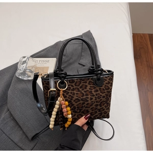 Secchiello leopardato con ciondolo in legno su un elegante sfondo di blazer grigio