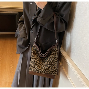 Detailed view of leopard print bucket bag with brown leather trim and adjustable strap