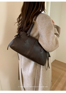 Detail of dark brown retro leather tote bag featuring side drawstrings and gold buckle