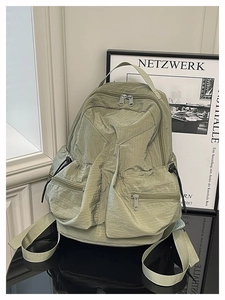 Detail of light green nylon outdoor backpack featuring functional pockets and drawstring ties
