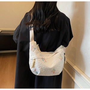 Model view showing the white crescent canvas crossbody bag with butterfly embroidery
