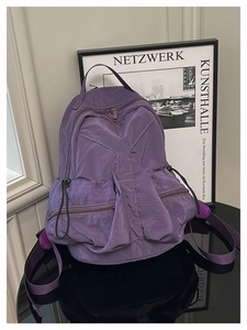 Detail view of purple nylon outdoor backpack with waterproof wrinkled texture and side drawstrings