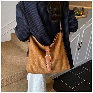 Detail of caramel brown woven hobo bag showing metallic buckle and premium texture