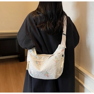 Detail of cream hobo bag featuring quilted fabric and colorful butterfly embroidery