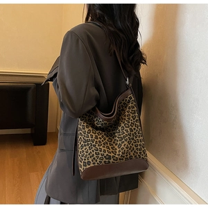 Detail of leopard print bucket bag with brown leather trim and adjustable shoulder strap