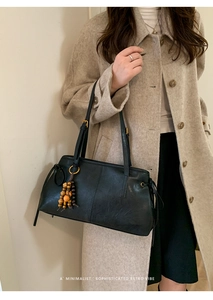Detail of minimalist black leather tote bag with unique wooden bead charm decoration