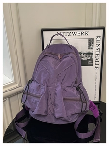 Detail of a purple nylon sports backpack with multiple pockets and drawstring adjusters
