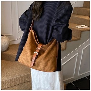 Close-up of brown suede bucket bag with woven texture and premium metal buckle detail