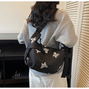 Detail of black crescent canvas bag with vibrant rainbow butterfly embroidery patterns