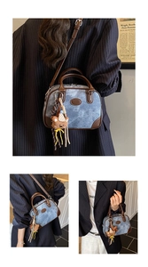 Detailed view of vintage denim Boston bag with brown leather handles and bear charm