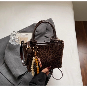 Dettaglio borsa a secchiello leopardata con texture cavallino e ciondolo in legno
