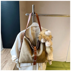 Detail of suede bucket bag featuring woven texture and faux fur accessory on the strap