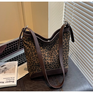 Close-up of leopard print bucket bag with dark brown leather trim and silver metal hardware