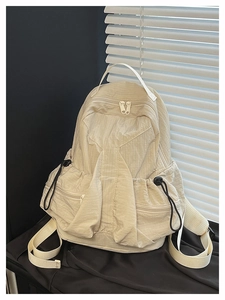 Detail of light beige ripstop nylon backpack showing functional cargo pockets and drawstrings