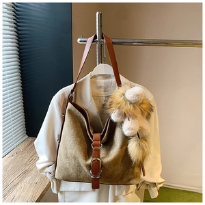 Detail of hobo bucket bag with brown woven texture and large decorative plush pom pom