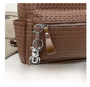 Detail of dark brown woven faux leather backpack texture with silver bear charm
