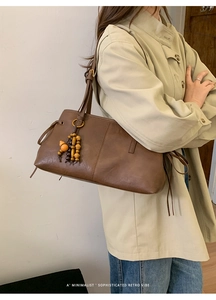 Detail of a brown leather tote with vintage wooden bead tassels and vertical stitching