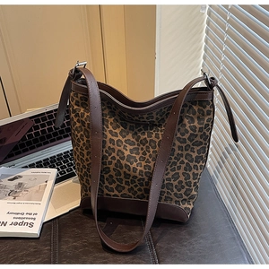 Detailed view of leopard print bucket bag with dark brown leather trim and metal buckles