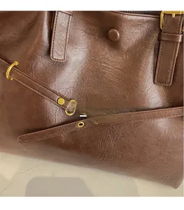 Close-up of vintage brown oily leather texture and premium gold hardware on tote bag