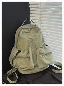 Detail view of a light green multi-pocket nylon backpack with high-quality texture and straps