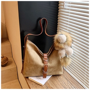 Detail view of beige woven tote bag with brown leather strap and lion plush charm