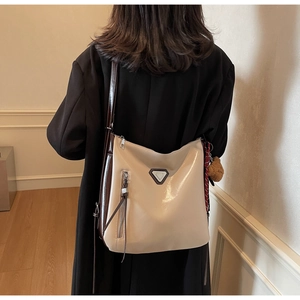 Model wearing a minimalist cream bucket bag with brown trim and cute bear charm detail