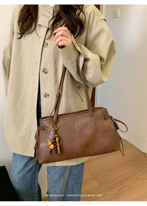 Detail of retro brown tote bag featuring fine leather texture and wooden bead pendant