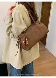 Close-up of brown vintage leather tote bag with drawstring details and beaded charms