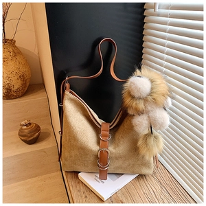 Detail of khaki suede hobo bag with leather straps and fluffy fur ball accessory