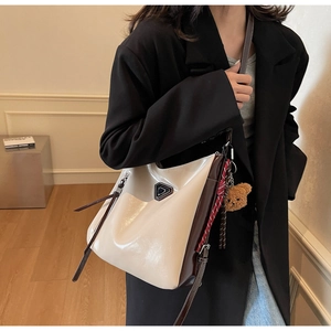 Detail of a chic tote bag featuring contrast stitching, metal hardware and a cute bear charm